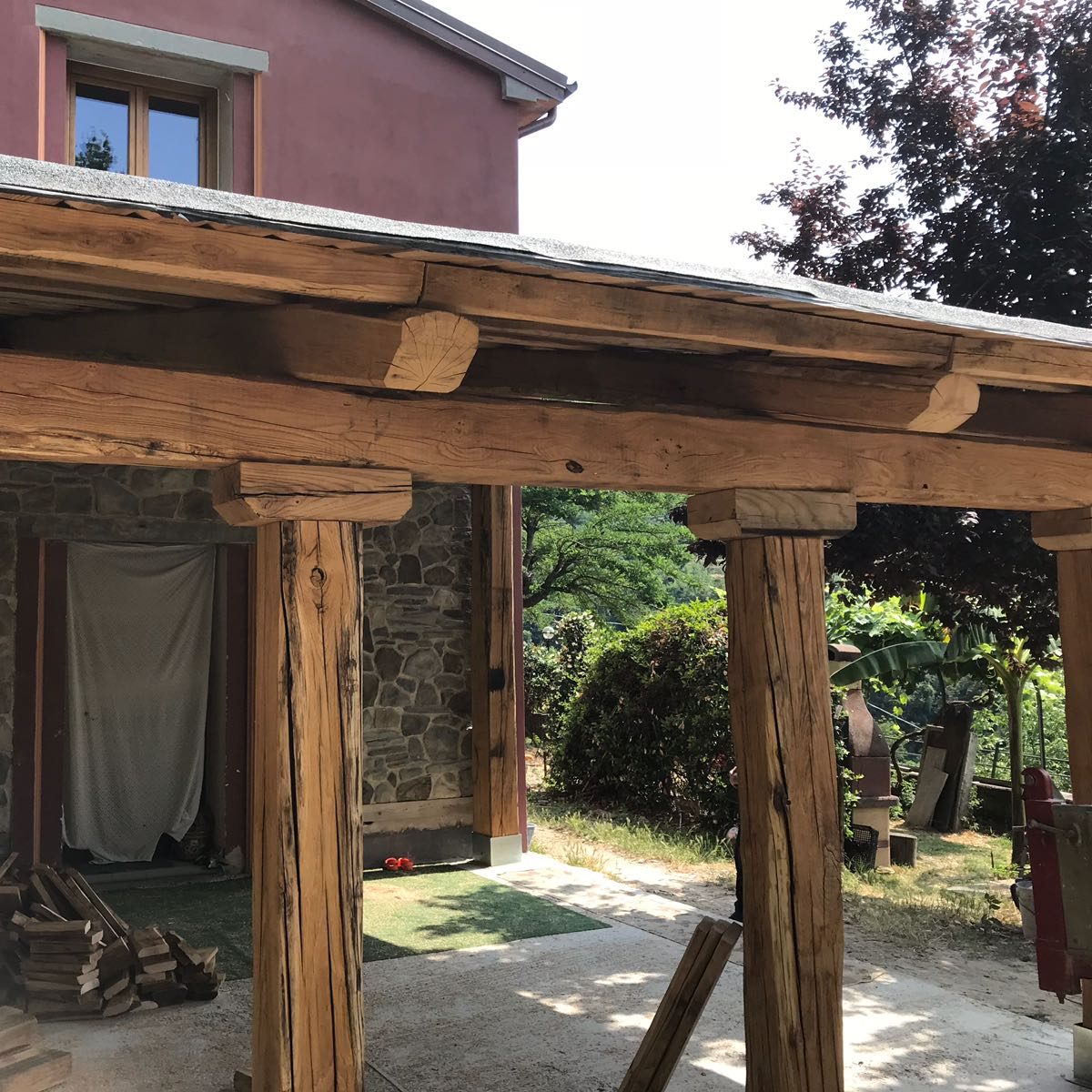 una struttura in legno di colore legno naturale, scura. una tettoia di una casa in campagna