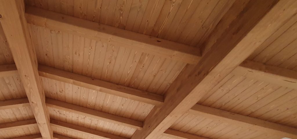 una copertura in legno di un marrone semichiaro, si vedono le assi di legno e le travi