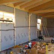 interno di una casa in legno in costruzione con visibile il materiale isolante ed il tetto con le assi in legno