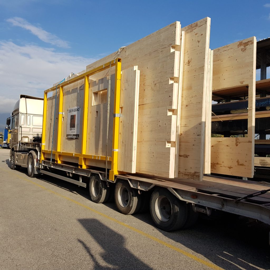 un camion, che porta delle grandi tavole di legno che andranno a fare parte di una casa in legno.