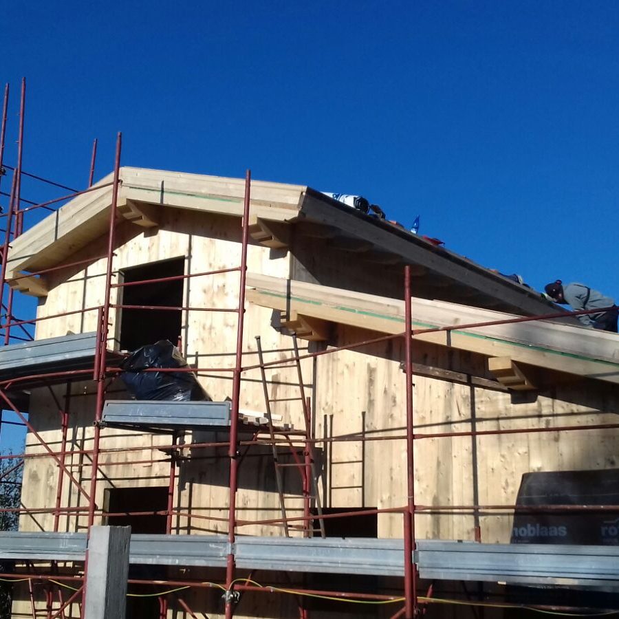 un casa in legno quasi del tutto costruita con delle impalcature intorno. La casa non presenta ancora gli infissi ma si vede il risultato quasi completo