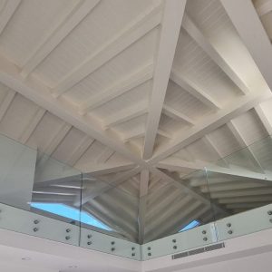 una copertura in legno bianca, si vedono le assi di legno e le travi ed una specie di terrazzino interno