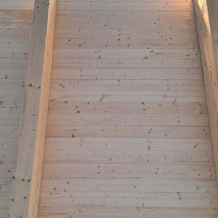 una copertura in legno bianca tendente al marrone chiaro, si vedono le assi di legno e le travi